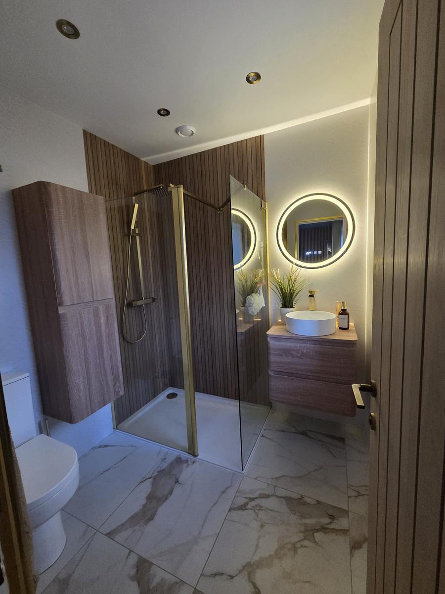 High-end en-suite renovation with brushed brass shower screen and vanity lighting
